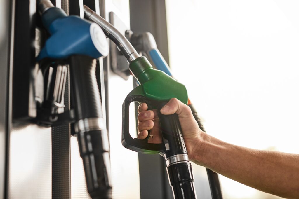 Crop man taking fuel pump nozzle at gas station